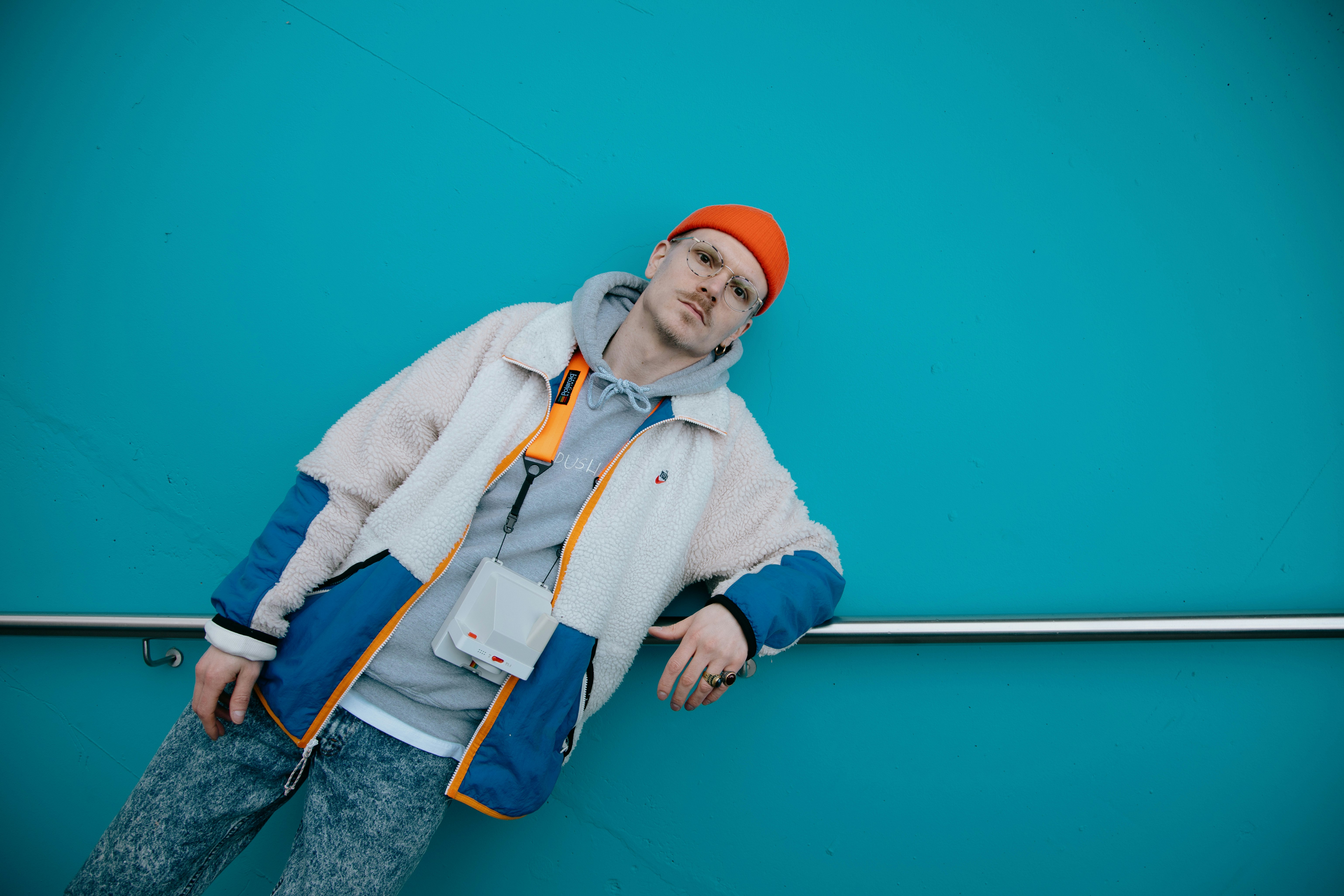 boy in white and blue jacket and orange cap